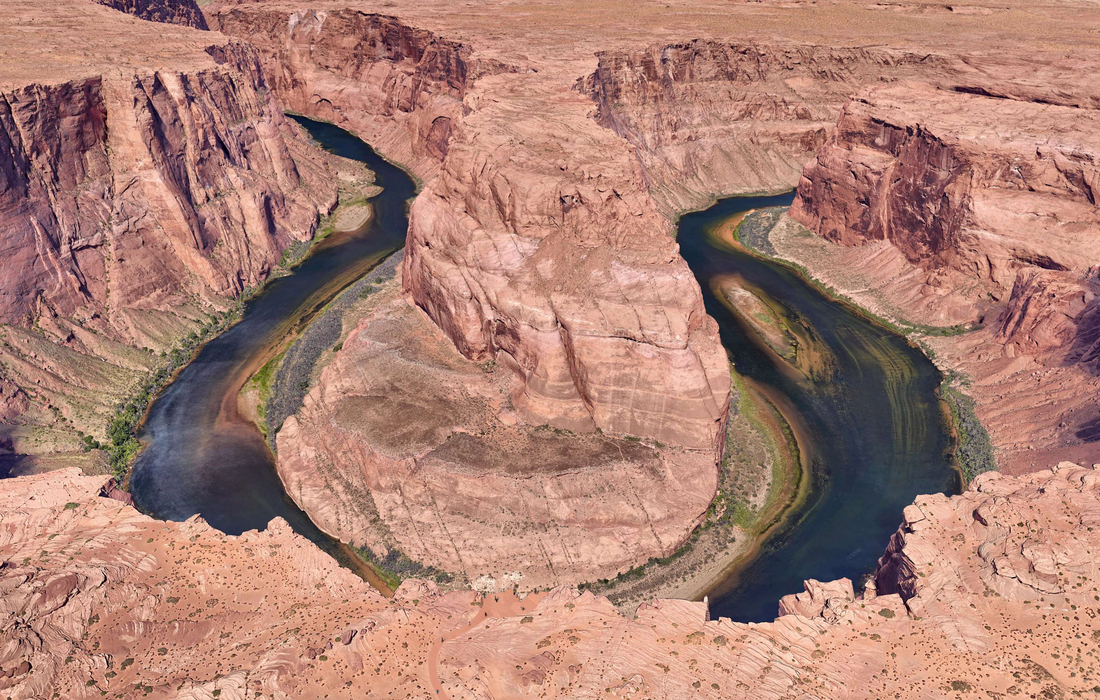 Aerial view of Horseshoe Bend in Arizona, featuring a sharp U-shaped meander of the Colorado River surrounded by steep, rocky cliffs in a desert landscape.