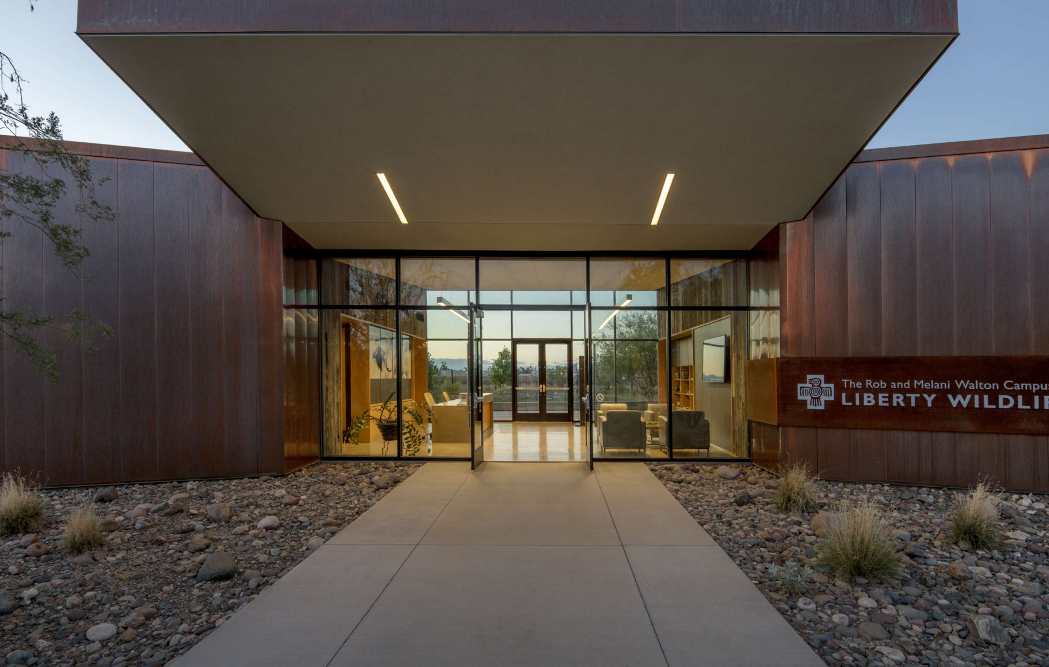 Exterior entrance of Liberty Wildlife's Rob and Melani Walton Campus featuring glass doors, a modern design, and a sign displaying the organization's name.