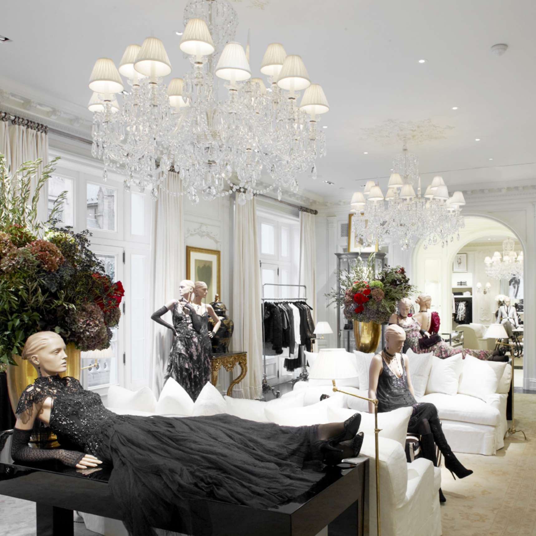 A luxurious boutique interior with a display case housing a black leather saddle. The surroundings are elegant with chandeliers and mirrored walls.